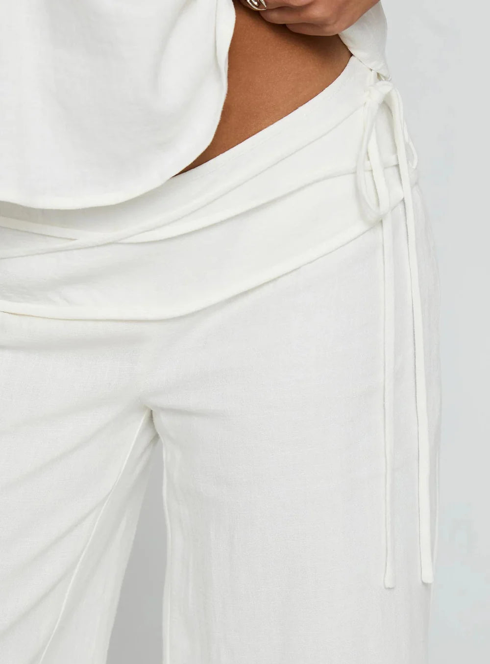 A pair of Linaro Riviera wide-leg trousers draped over a chair in soft window light
